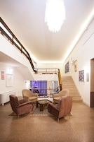 Una sala de estar moderna con una escalera, una araña y obras de arte en las paredes.