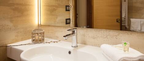 A bathroom with a white sink, a mirror, a hairdryer, and a towel.