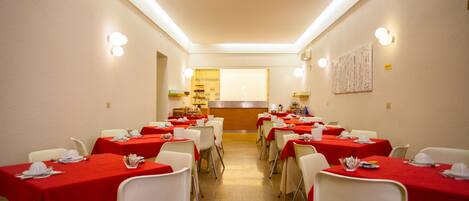 Un comedor con mesas dispuestas para una comida, que cuenta con una barra central y un panel de menú colgado en la pared.
