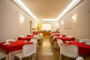 A dining area with tables set for a meal, featuring a central counter and a wall-mounted menu board. - Hotel Italia (Cagliari)