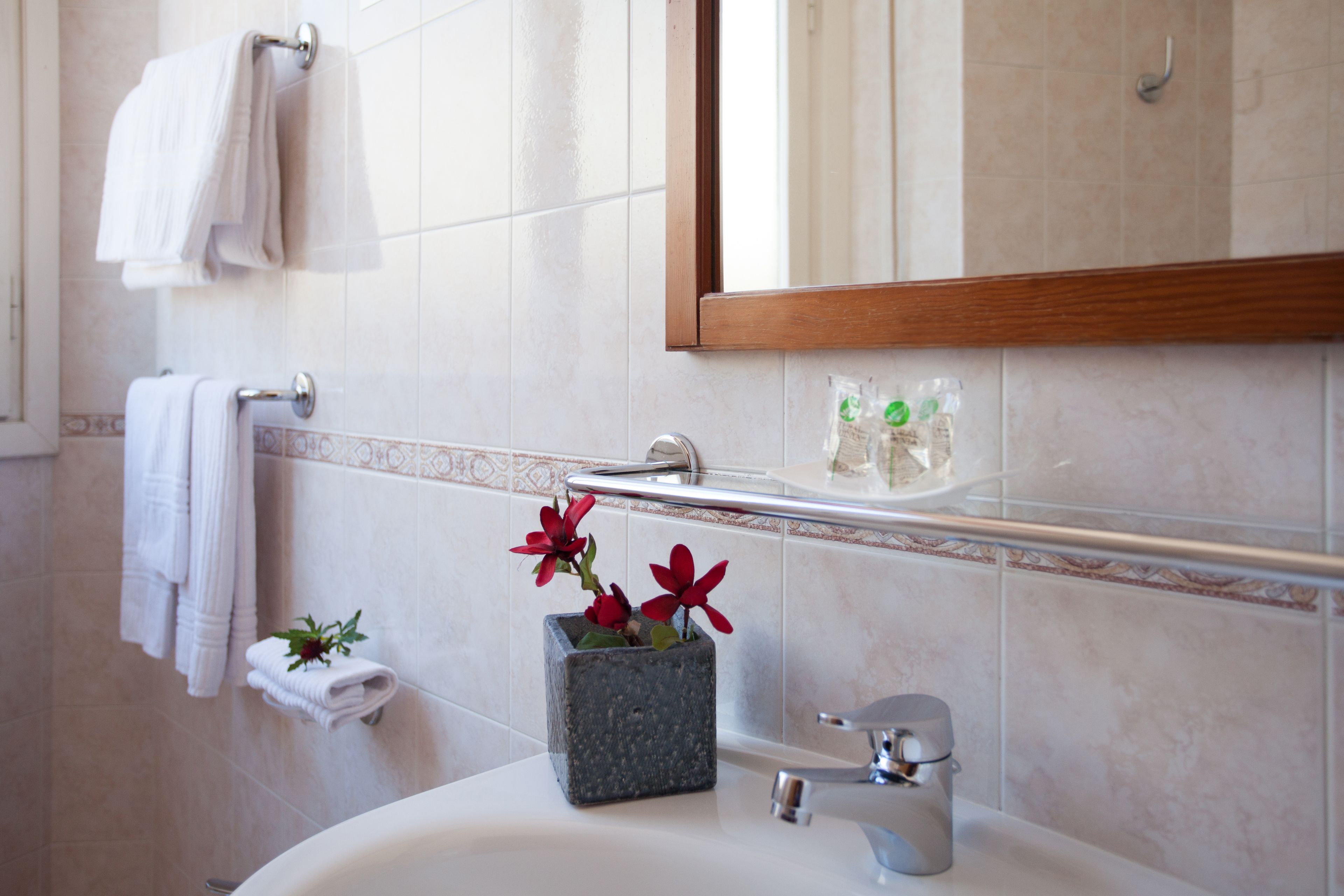 A bathroom with a white sink, a mirror, and a towel rack with folded towels.
