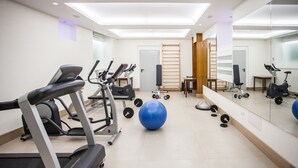 Un gimnasio con cintas de correr, pelotas de ejercicio y equipo de pesas.