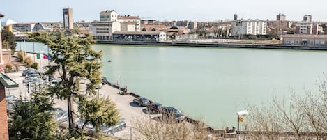A waterfront view with buildings, a parking area, and a clear sky.