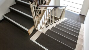 Una escalera con barandilla y piso alfombrado.