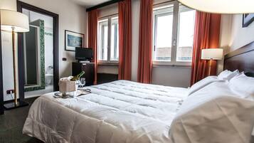 Une chambre d’hôtel avec un grand lit, une télévision, un minibar et une fenêtre avec des rideaux.