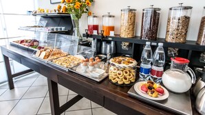 Un bufé con diversas opciones de comida, como pasteles, frutas y bebidas.