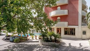 Ein mehrstöckiges Gebäude mit Balkonen, einem Pool und umgebender Bepflanzung.