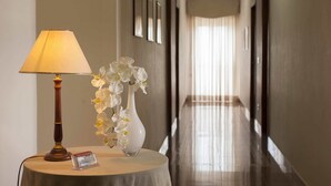 Ein Hotelkorridor mit einer Lampe und einer weißen Blumenvase auf einem runden Tisch.