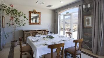 A dining area with a table set for four, a potted plant, a mirror, and a view of the outdoors.