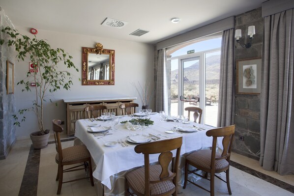 Comedor con una mesa preparada para cuatro personas, una planta en maceta, un espejo y vistas al exterior.