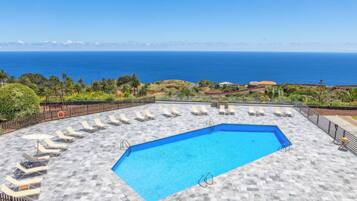 Een buitenzwembad, parasols voor strand/zwembad