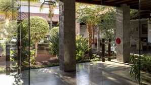 A spacious indoor courtyard with a tiled floor, large glass windows, and a variety of tropical plants. - Parador de La Palma (Brena Baja)
