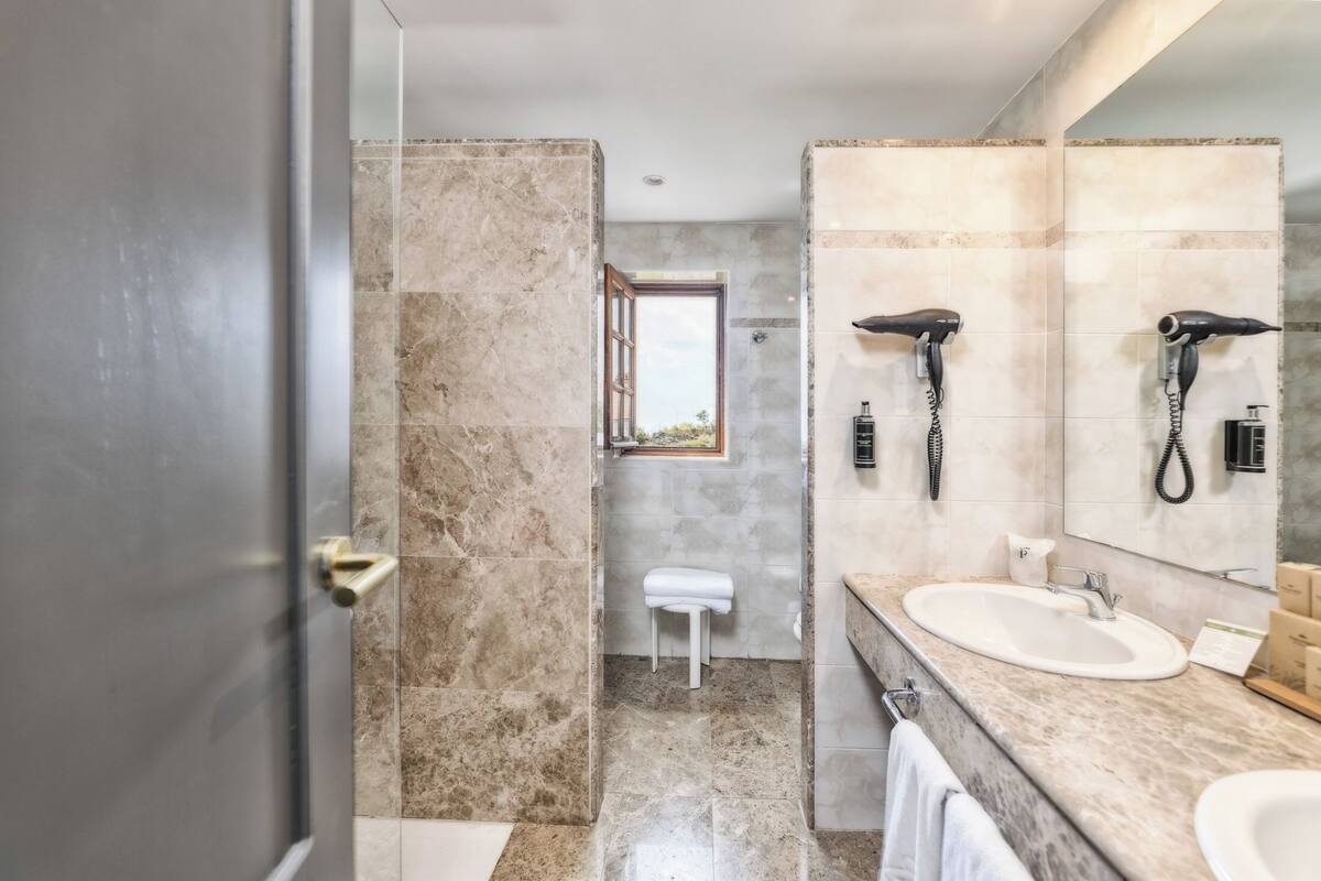 Un baño moderno con un espejo grande, dos lavamanos, un secador de pelo y un perchero para toallas.