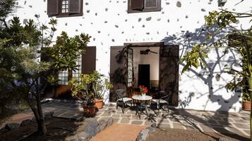 A patio with a stone floor, potted plants, and a table with chairs.