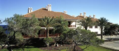 A large house with a tiled roof, surrounded by a well-maintained garden with various trees and shrubs.