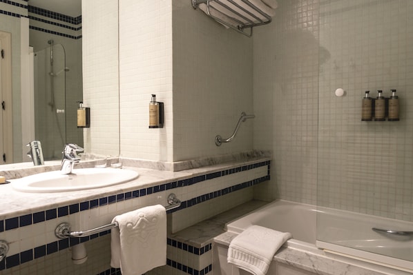 A bathroom with a double sink, a bathtub, and a glass shower enclosure.