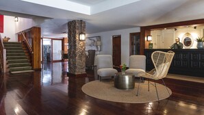 A spacious living area with a stone pillar, a staircase, and a reception desk. - Parador de El Hierro (Valverde)