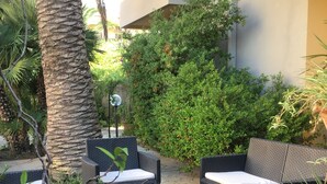 An outdoor seating area with wicker furniture and a stone floor. - Hotel Mistral (Alghero)