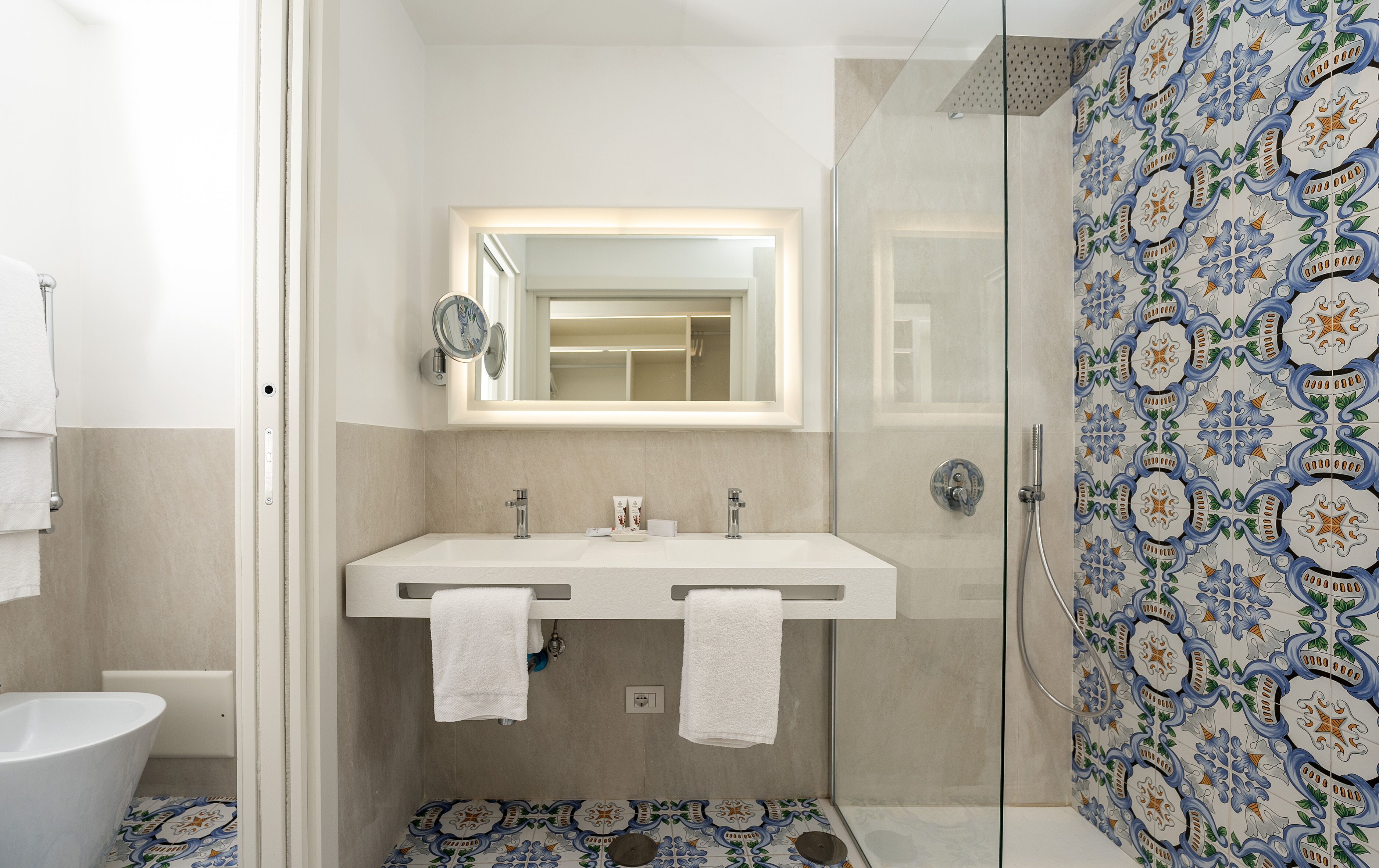 A bathroom with a double sink, a mirror, and a shower.