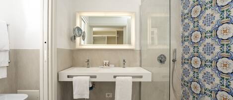 A bathroom with a double sink, a mirror, and a shower.