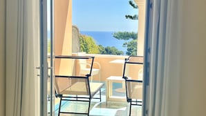 A balcony with a glass door, white curtains, and a view of the sea. - Hotel La Vega (Capri)