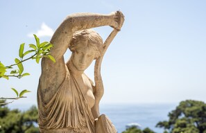 A statue of a figure with a raised arm, set against a clear sky and ocean view. - Hotel La Vega (Capri)