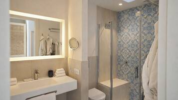 Un baño moderno con ducha envuelta en vidrio, un espejo grande y un lavabo con toallero.