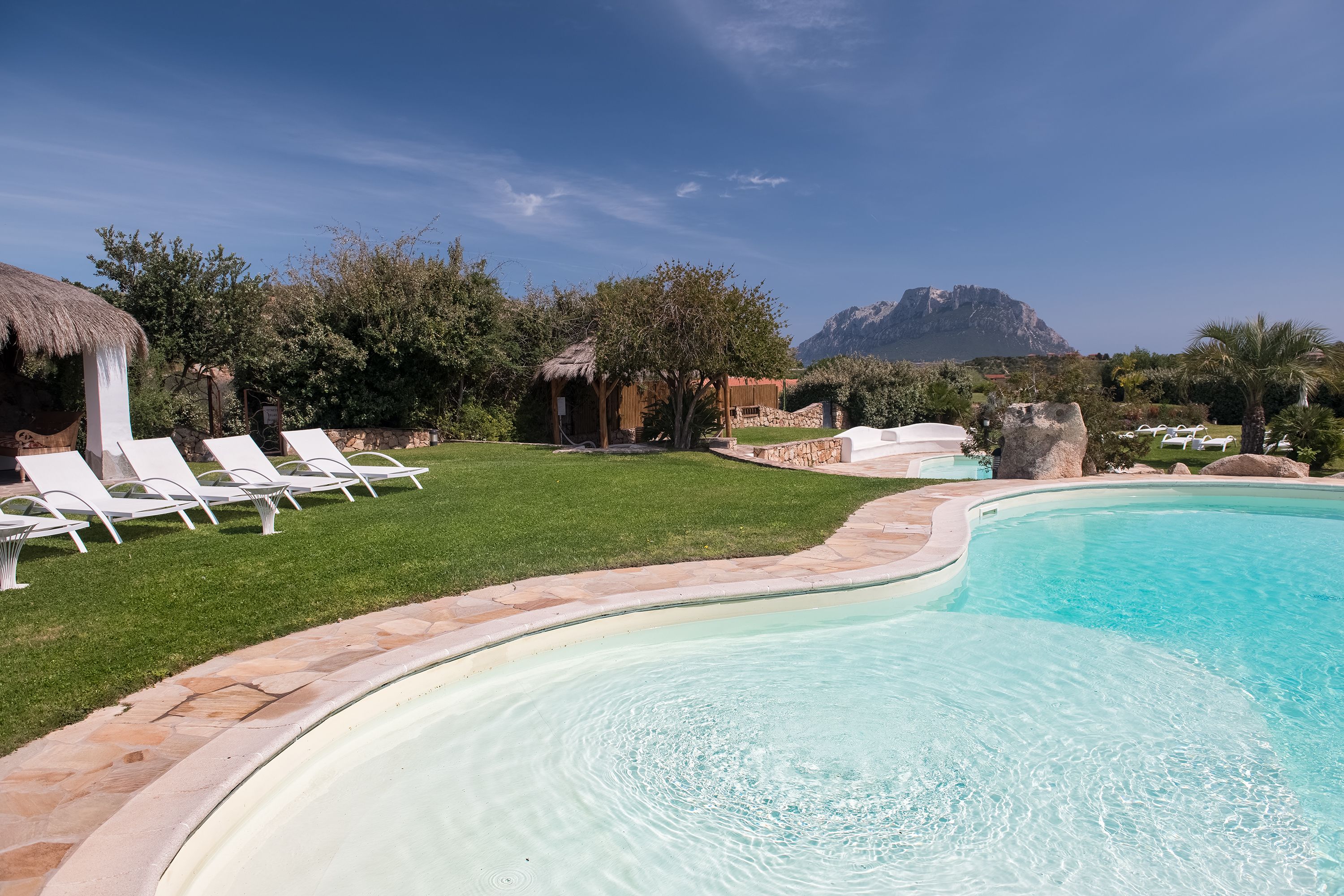 Ein Swimmingpool mit Liegestühlen und einem Berg im Hintergrund.
