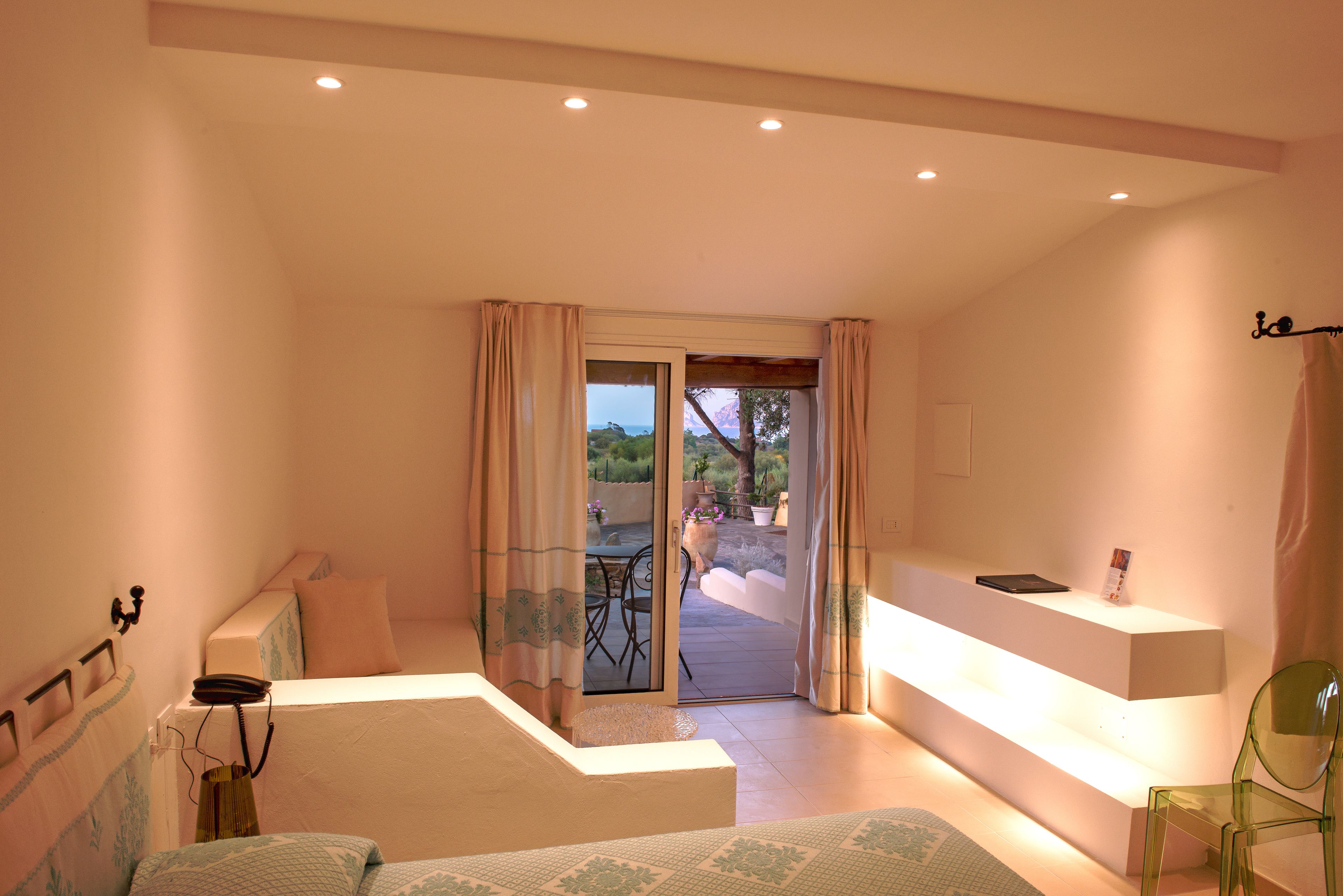 Un dormitorio con una cama, un escritorio y una silla. Hay un ventanal corredero que da a un espacio exterior.