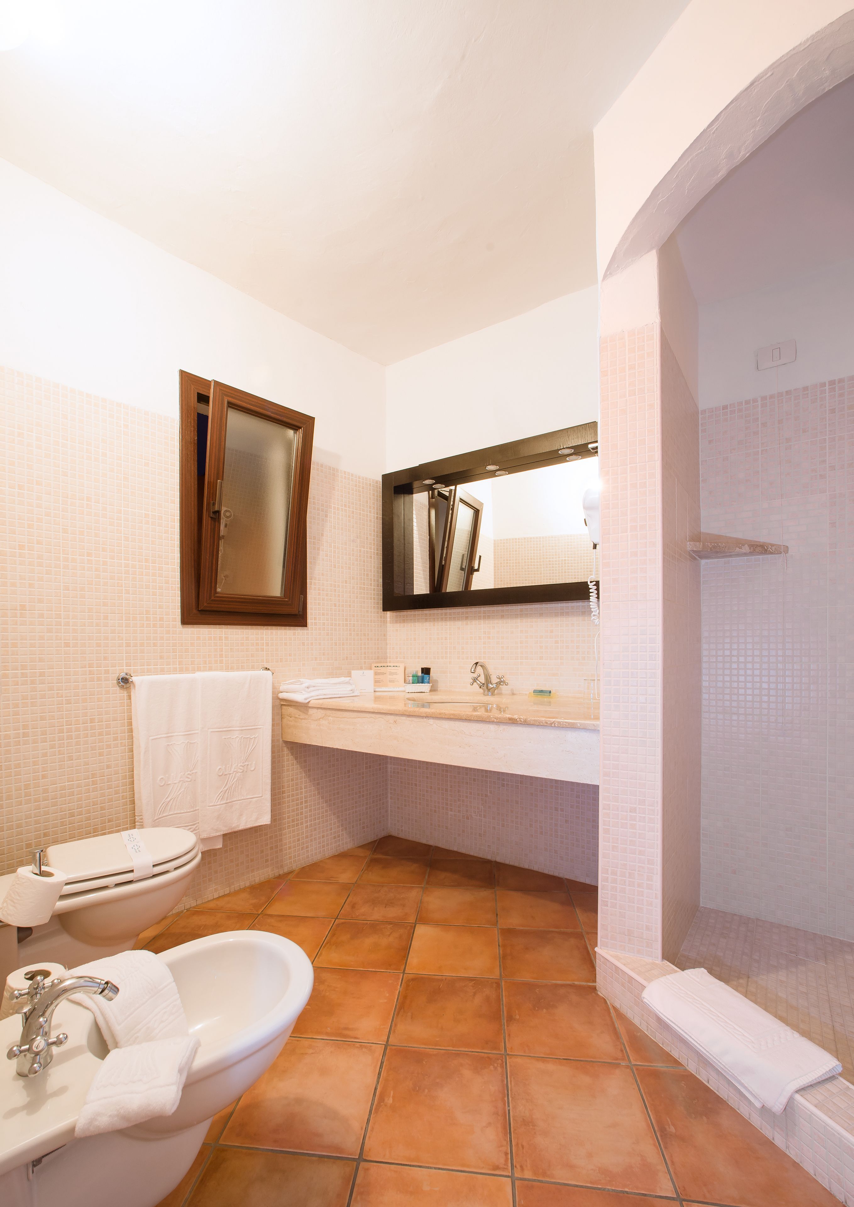 A bathroom with a toilet, sink, and bathtub. There is a mirror above the sink and a shower area to the right.