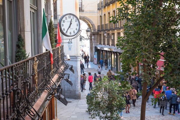 A busy urban street with a clock tower, shops, and pedestrians. - Petit Palace Posada del Peine (Madrid)