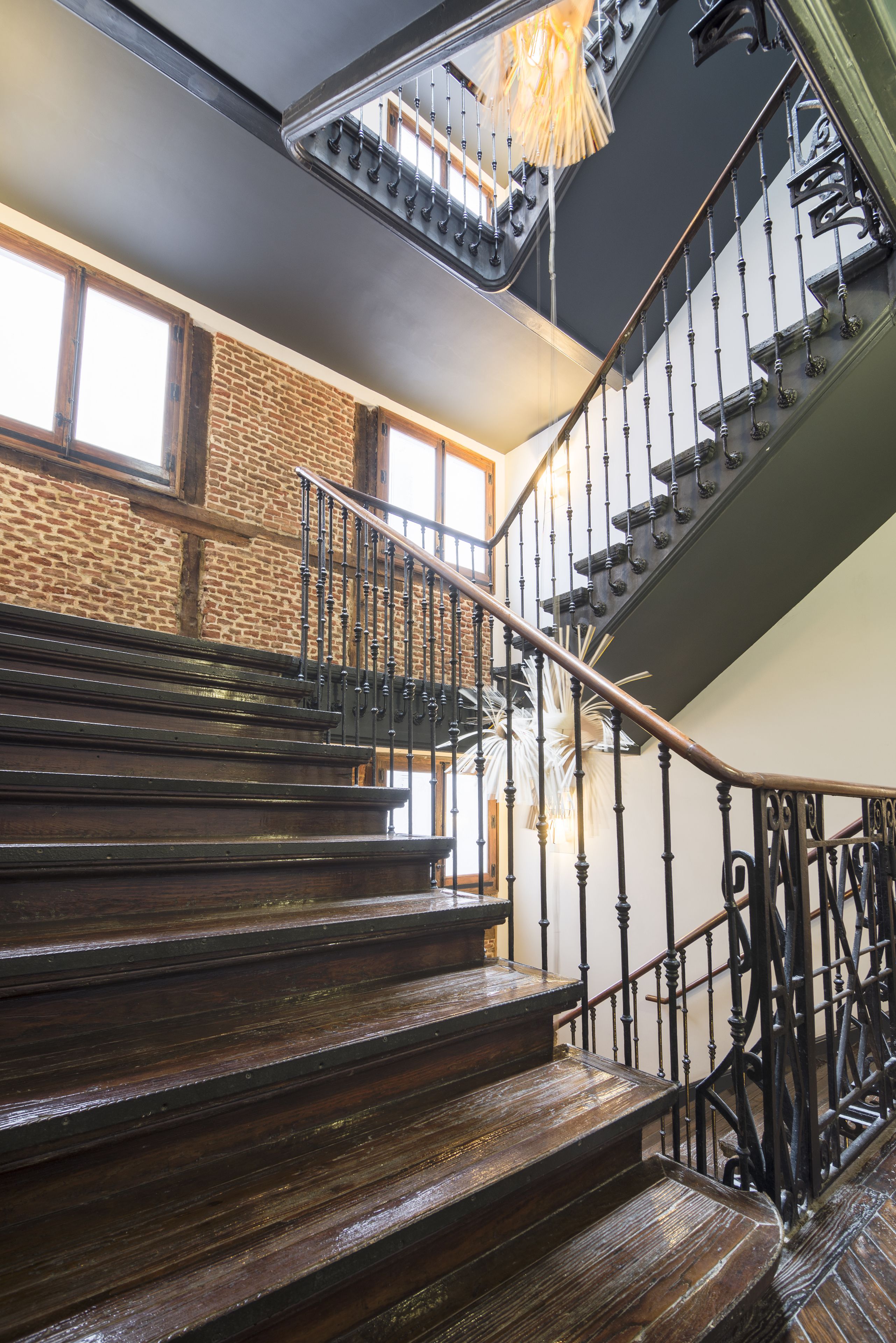 A wooden staircase with a wrought iron railing leading to a second floor.