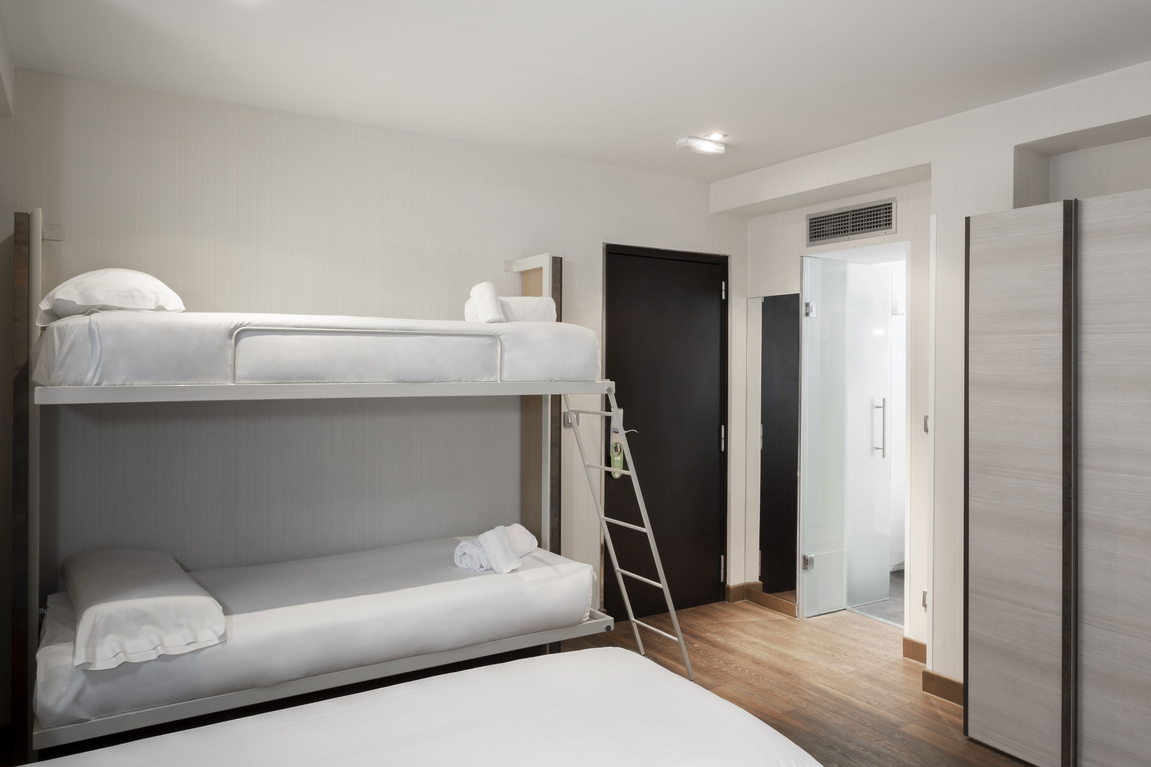 Habitación con literas, una escalera, una puerta y un armario.