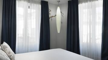 Un dormitorio con una cama grande, cortinas oscuras y una lámpara fijada a la pared.