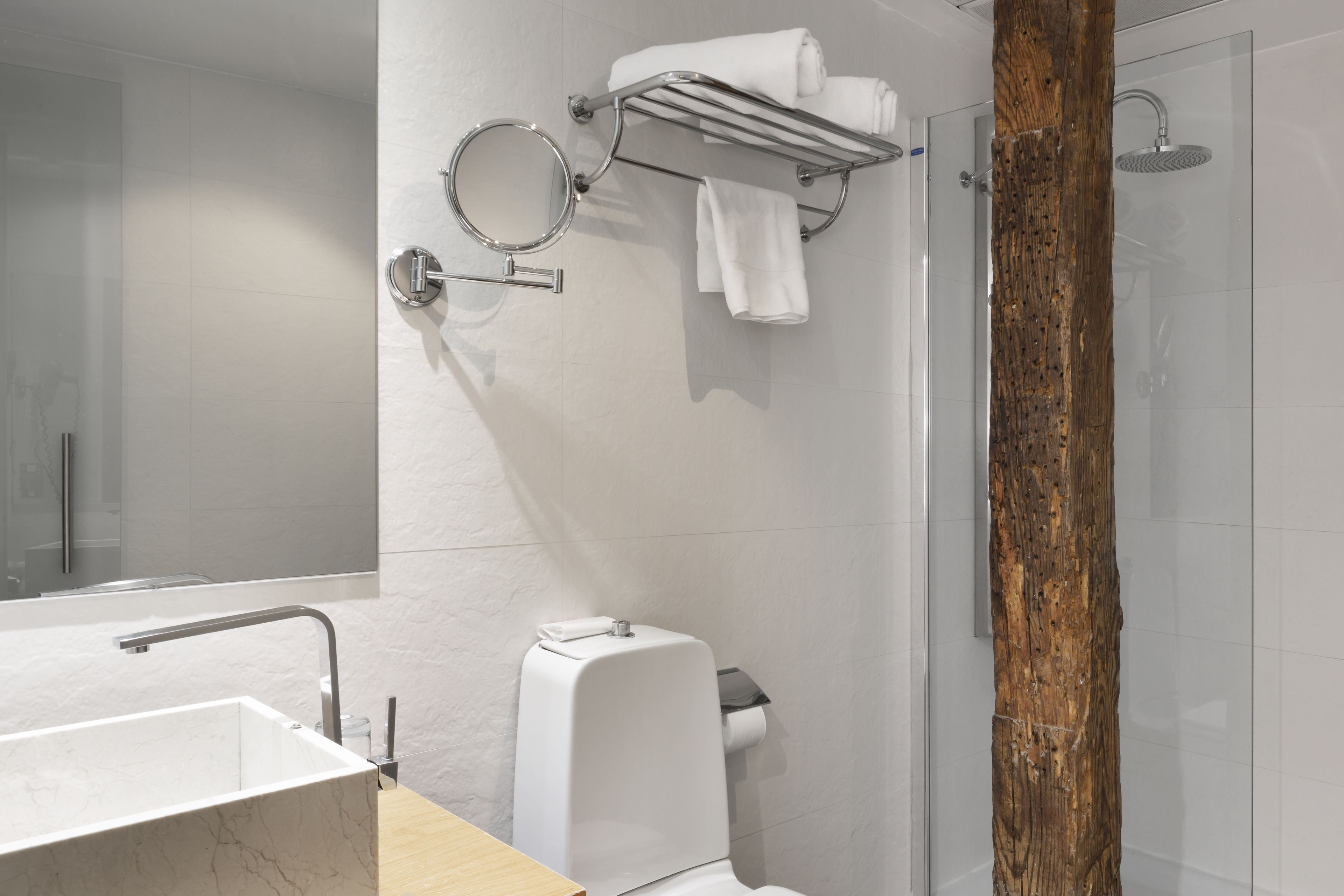 A modern bathroom with a marble sink, a toilet, a shower, and a wooden accent wall.