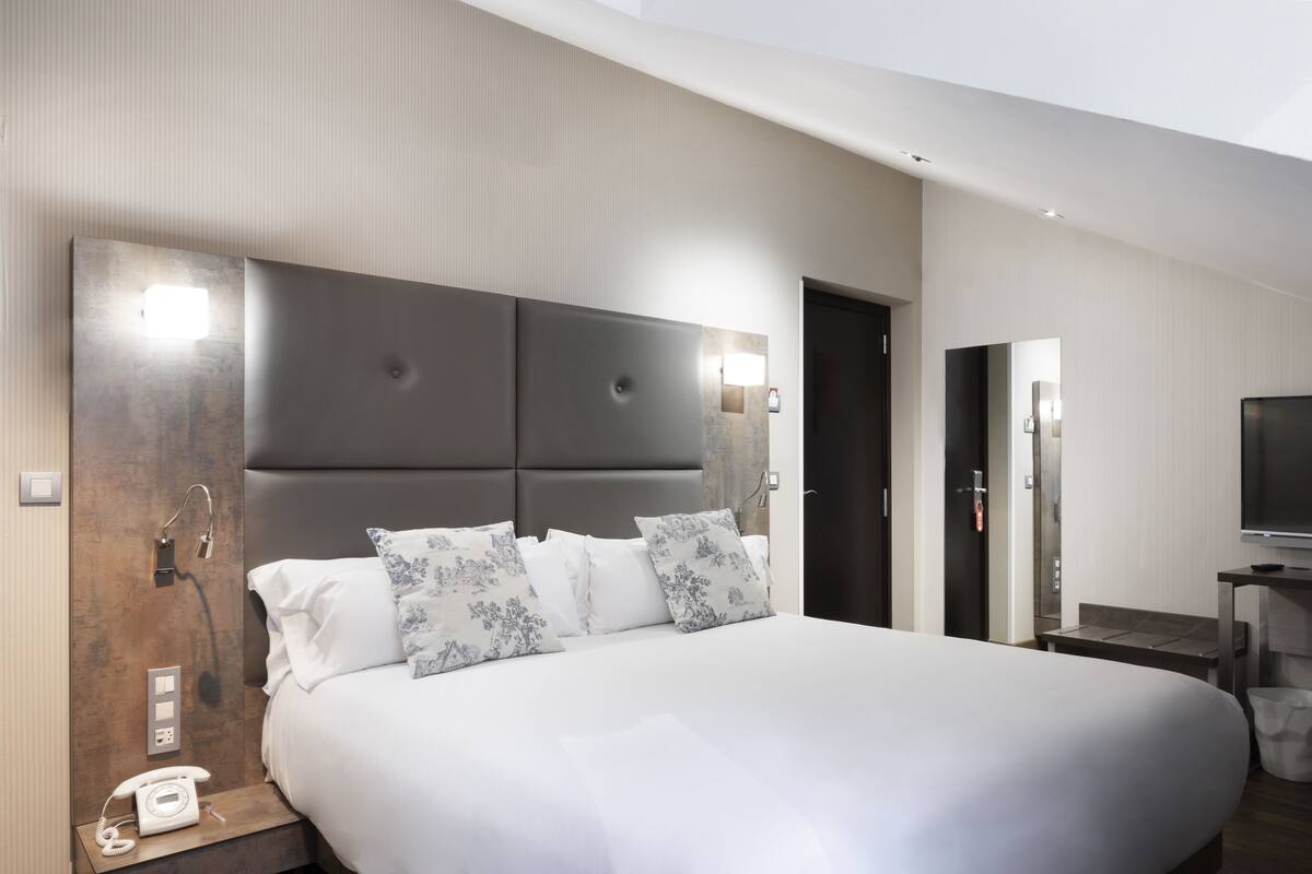 Une chambre d’hôtel moderne dotée d’un grand lit, d’un téléphone sur la table de chevet et d’un téléviseur à écran plat.