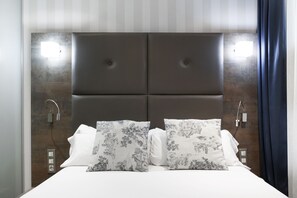 A modern bedroom with a large bed, two bedside tables, and a headboard with integrated lighting. - Petit Palace Posada del Peine (Madrid)