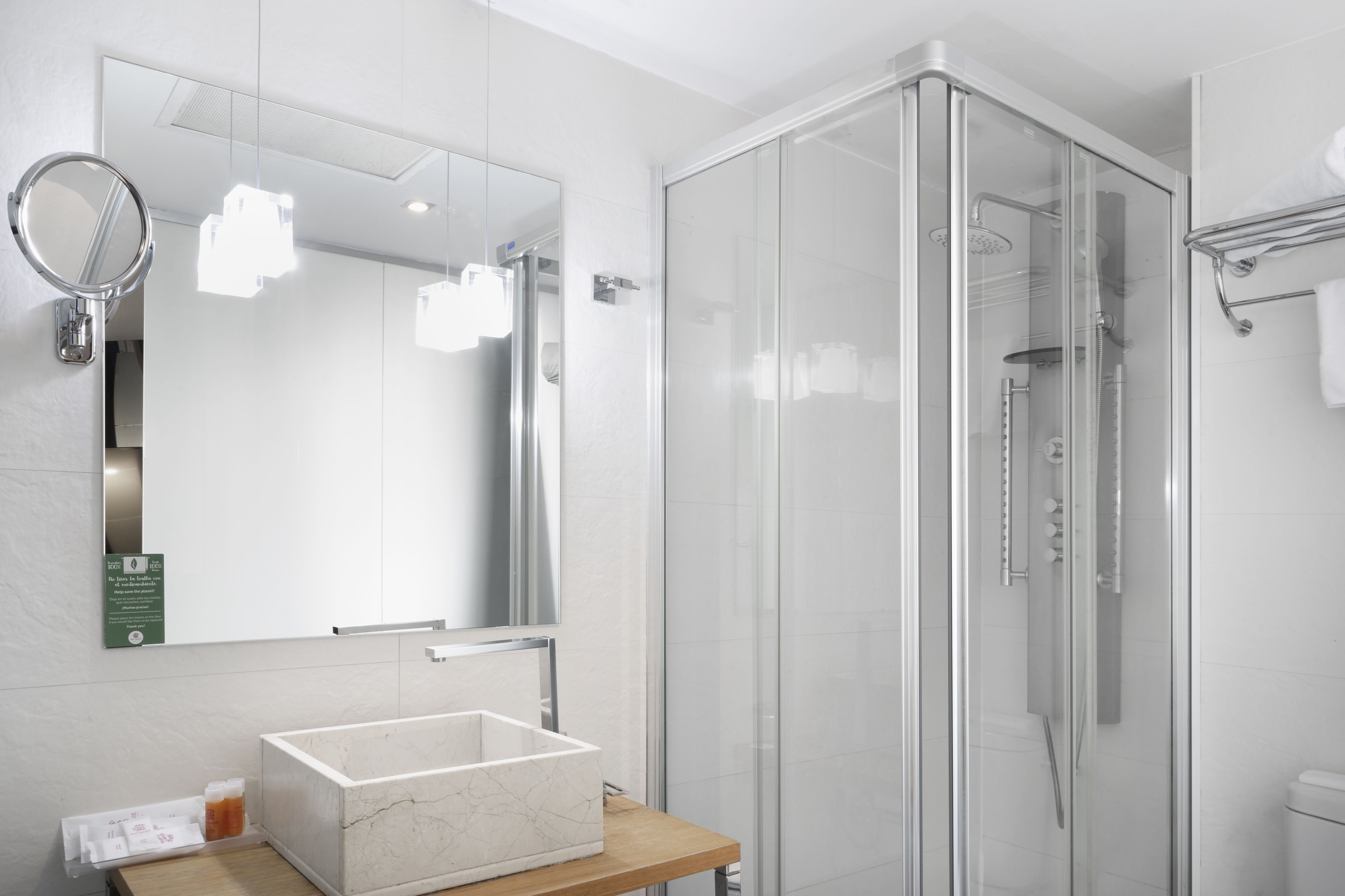 A modern bathroom with a glass-enclosed shower, a marble sink, and a large mirror.