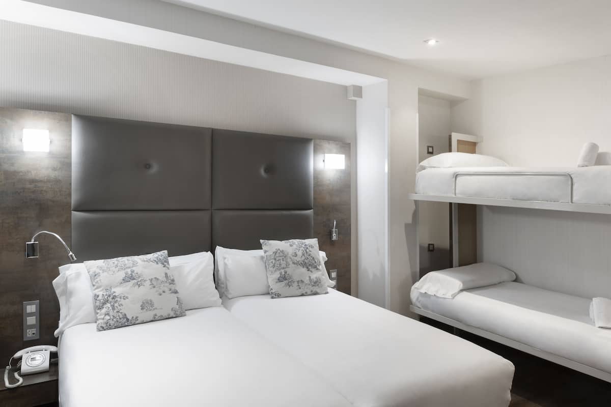 Une chambre d’hôtel moderne avec un grand lit, un téléphone sur la table de chevet et un lit superposé.