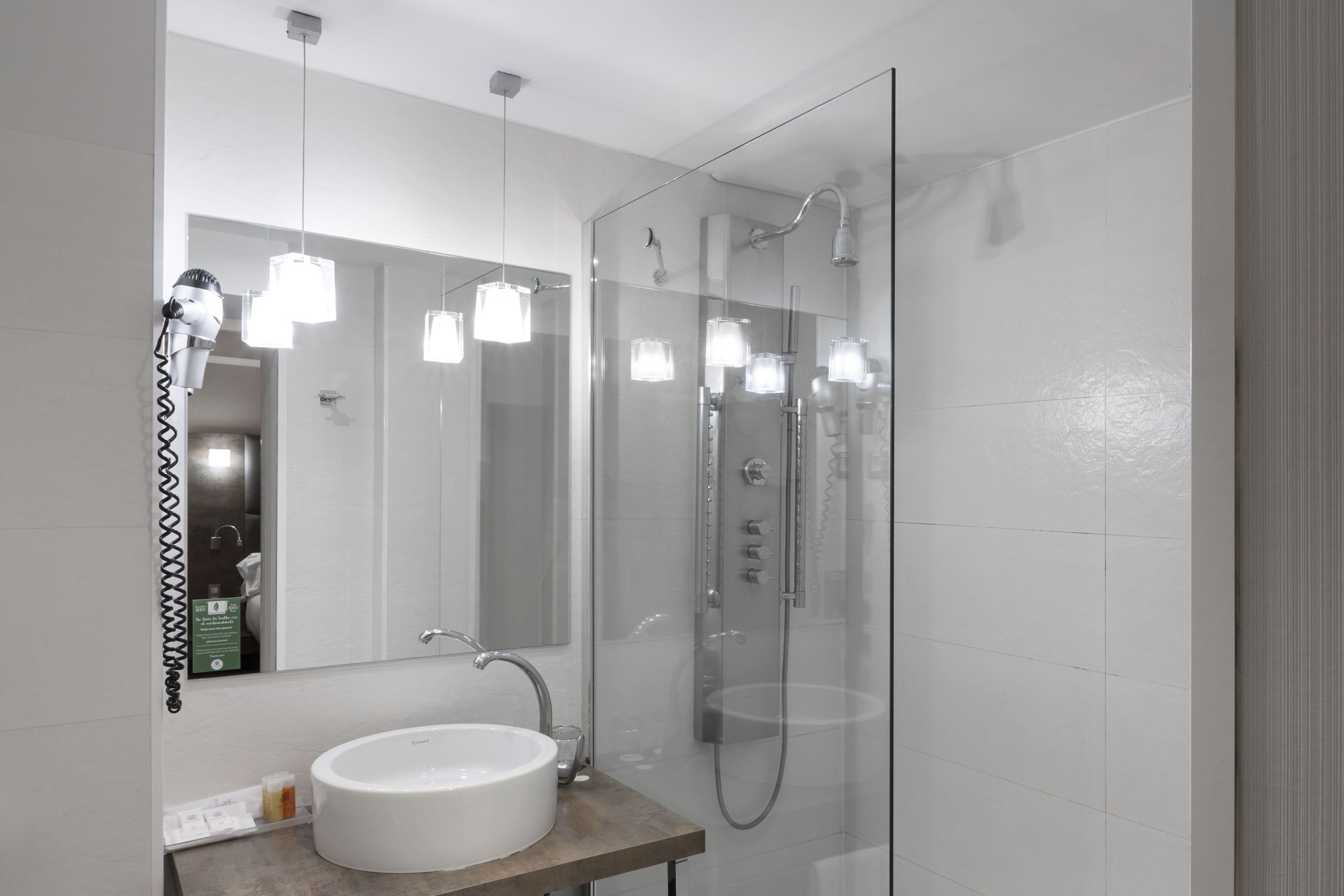 A modern bathroom with a glass-enclosed shower, a white sink, and a mirror above the sink.