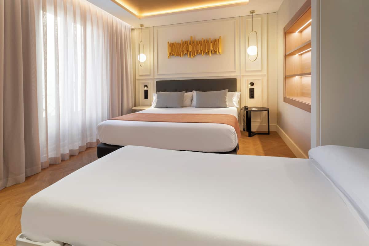 A modern hotel room with a large bed, a bedside table, and a wall-mounted light fixture.