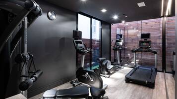Une salle de sport moderne équipée de divers appareils d’exercice, notamment un tapis de course, un vélo elliptique et des appareils de musculation.