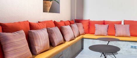 A modern outdoor seating area with a curved bench and two round tables.