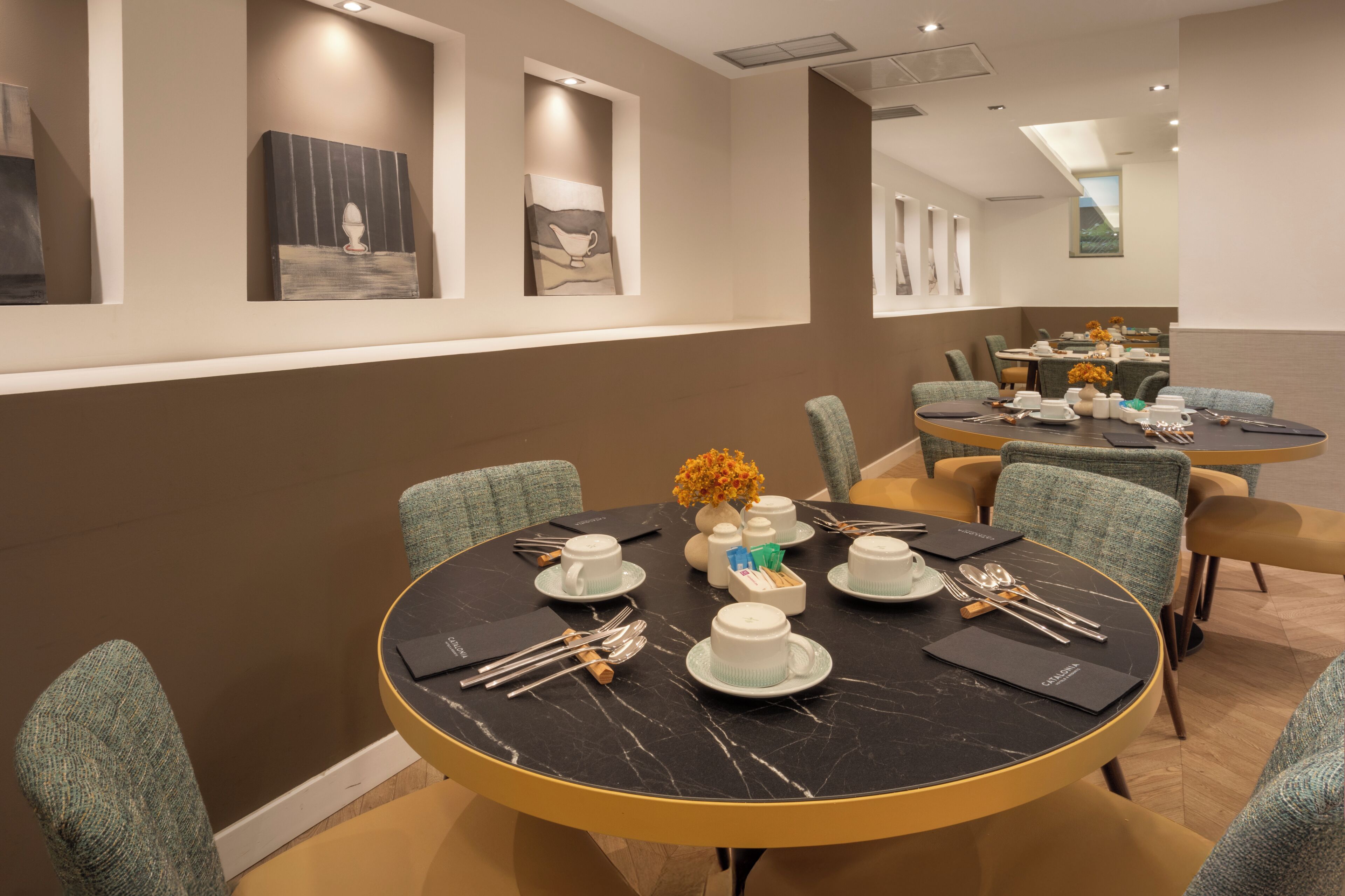 A modern dining area with round tables, chairs, and a variety of tableware.