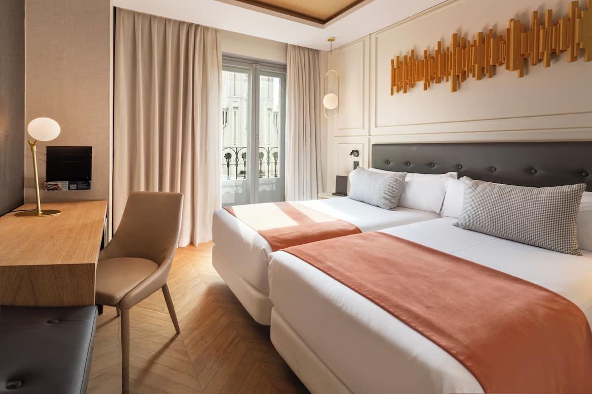 A hotel room with a bed, a desk, and a chair.