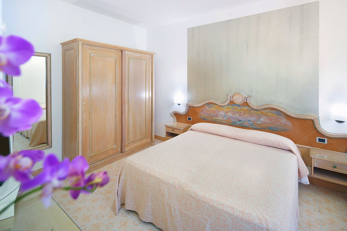 Un dormitorio con cama, armario, mesita de noche y una pared decorada con un cuadro.