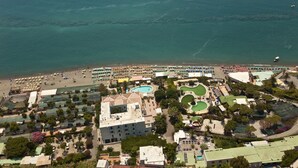 Luftaufnahme eines Küstenresorts mit Strand, Schwimmbad und mehreren Hotelgebäuden.