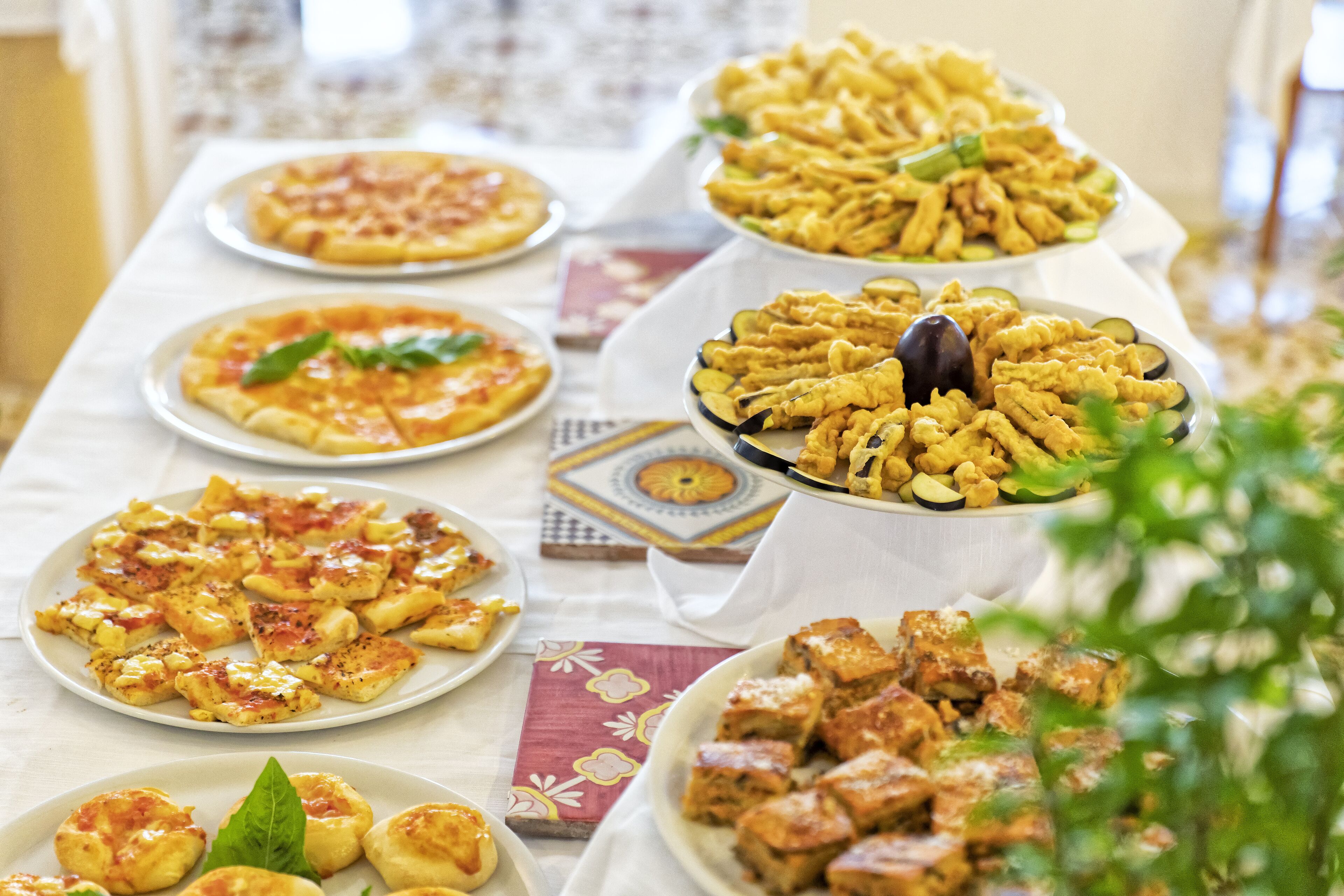 Ein Tisch mit verschiedenen Speisen, darunter Pizza, frittierte Gerichte und Desserts.
