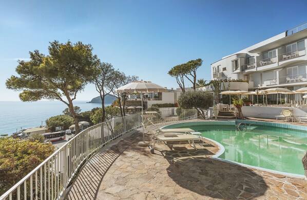 A pool area with lounge chairs, umbrellas, and a view of the sea. - Hotel San Giorgio Terme (Barano d'Ischia)
