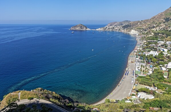 A coastal town with a beach, clear blue waters, and buildings along the shore.